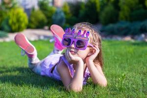 adorable petite fille dans des verres de joyeux anniversaire souriant en plein air photo