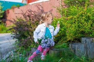 petite fille mignonne marchant avec un bouquet de fleurs photo