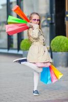 adorable petite fille marchant avec des sacs à provisions à l'extérieur photo