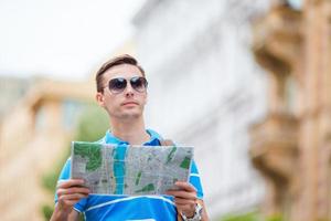 homme touriste avec un plan de la ville et un sac à dos en europe. garçon caucasien regardant la carte de la ville européenne à la recherche d'attractions. photo