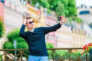 homme touristique prenant des photos de voyage avec un smartphone pendant les vacances d'été. jeune touriste attrayant prenant une photo de selfie avec un téléphone portable à l'extérieur profitant d'une destination de voyage de vacances dans le tourisme et explorant le concept