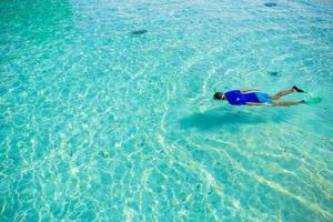 jeune homme plongée en apnée dans des eaux turquoises tropicales claires photo