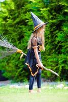 adorable petite fille portant un costume de sorcière avec un balai à l'extérieur d'halloween photo