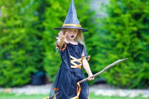 adorable petite fille portant un costume de sorcière avec un balai à l'extérieur d'halloween photo