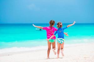 petites filles s'amusant à la plage tropicale pendant les vacances d'été jouant ensemble en eau peu profonde photo