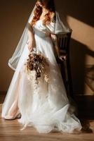 Portrait d'une jeune mariée aux cheveux rouges dans une robe de mariée blanche photo