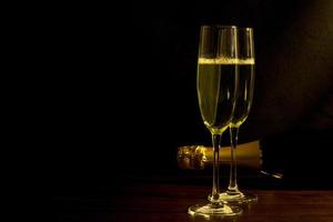 concept de fête festive, verre de champagne avec bouteille de champagne sur table en bois sur fond noir photo