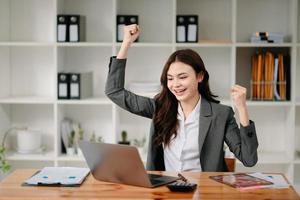 les femmes d'affaires sont ravies et satisfaites du travail qu'elles font sur leur tablette, leur ordinateur portable et de prendre des notes au bureau moderne. photo