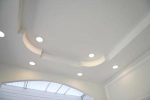 plafond tendu de forme blanche et complexe. plafond avec lampes halogènes et construction de cloisons sèches dans une pièce vide du hall d'exposition ou de la maison. photo
