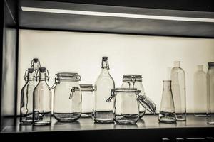 une exposition d'objets en verre, groupe de bouteilles et bocaux en noir et blanc