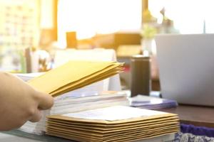 le flou du commis de bureau ou de la secrétaire prépare des documents et des enveloppes brunes pour les personnes intéressées à soumissionner pour la construction d'un grand bâtiment dans un bureau. photo