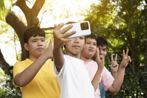 groupe de jeunes adolescents asiatiques passant du temps libre dans le parc à se raser les doigts et à prendre un selfie ensemble avec bonheur, une mise au point douce et sélective sur un garçon en t-shirt blanc, élevant le concept d'adolescents. photo