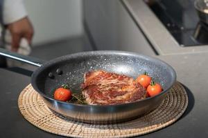 steak cuit et grillé sur une poêle avec un peu de tomate, et faites une pause sur une assiette en osier pour la prochaine étape. photo