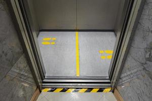 distanciation sociale pour covid-19 avec panneau d'empreinte jaune dans l'ascenseur public photo
