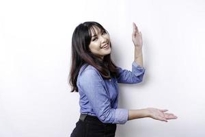 femme asiatique excitée portant une chemise bleue pointant vers l'espace de copie à côté d'elle, isolée par fond blanc photo