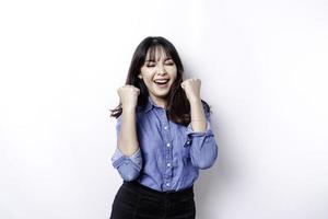 une jeune femme asiatique avec une expression heureuse et réussie portant une chemise bleue isolée par fond blanc photo