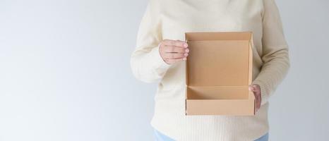mains de femme portant une boîte en carton d'ouverture brune. concept d'utilisation d'une boîte de papier recyclé. photo