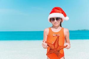 adorable petite fille avec des étoiles de mer sur une plage vide blanche photo