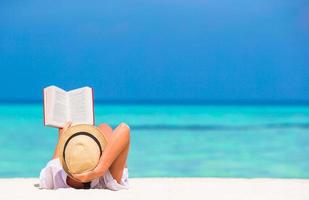 jeune femme lisant un livre pendant une plage blanche tropicale photo