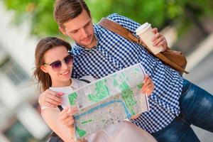 heureux couple de touristes voyageant en europe souriant heureux. amis caucasiens avec plan de la ville à la recherche d'attractions. jeune homme avec un café chaud et une belle femme avec une grande carte photo