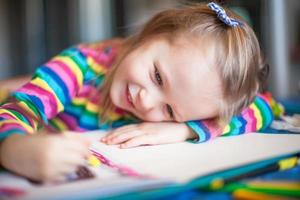 petite fille mignonne peinture avec des crayons tout en étant assis à sa table photo