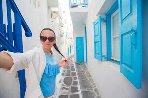 belle jeune femme prenant selfie avec téléphone extérieur fond maison blanche photo