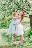 adorables petites filles dans un jardin de pommiers en fleurs le jour du printemps photo