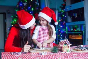 adorable fille avec sa mère préparant des biscuits de noël dans la cuisine photo