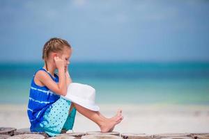 petite fille adorable écoutant de la musique sur des écouteurs sur la plage photo