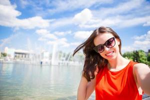 jeune femme caucasienne faisant selfie sur fond d'attractions à l'extérieur photo