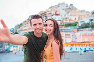 vacances d'été en italie. jeune couple dans le village de positano en arrière-plan, côte amalfitaine, italie photo