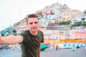 vacances d'été en italie. jeune homme dans le village de positano en arrière-plan, côte amalfitaine, italie photo