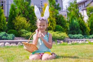 adorable petite fille portant des oreilles de lapin tenant un panier avec des oeufs de pâques photo