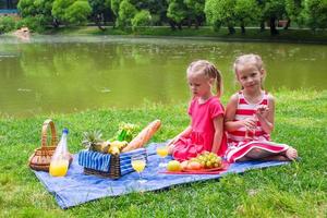 adorables petites filles pique-niquer dans le parc aux beaux jours photo