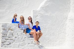 vacances en famille en europe. parents et enfants assis sur les marches de l'église paraportiani sur l'île de mykonos, en grèce photo