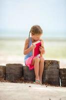 petite fille adorable avec livre sur la plage blanche tropicale photo