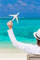 vue arrière de l'homme avec la miniature d'un avion à la plage tropicale photo
