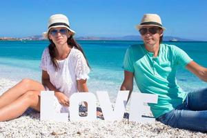 jeune belle famille assise sur la plage avec le mot amour photo