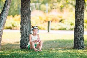 petite fille adorable écoutant de la musique dans le parc photo