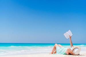 jeune femme lisant un livre pendant une plage blanche tropicale photo