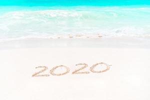 écrit à la main sur une plage de sable avec une douce vague océanique sur fond photo