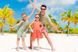 le père et les petites filles s'amusent beaucoup sur la plage de sable blanc photo