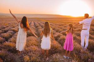 famille dans le champ de fleurs de lavande au coucher du soleil en robe blanche et chapeau photo