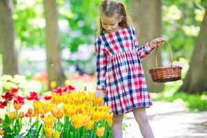 petite fille adorable avec des fleurs dans le jardin de tulipes photo