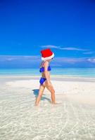 petite fille en bonnet de noel sur la plage pendant les vacances photo