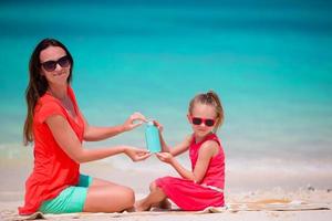 famille avec crème de bouteille de soleil sur la plage blanche photo