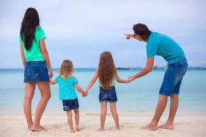 vue arrière d'une jeune famille avec deux filles sur une plage exotique aux beaux jours photo