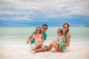 belle jeune famille avec deux filles s'amusant à la plage photo