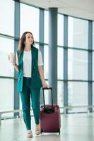 jeune femme un salon d'aéroport à l'aéroport international marchant avec du café et des bagages photo