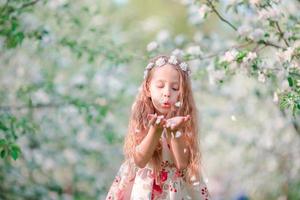 adorable petite fille dans un jardin de cerisiers en fleurs le jour du printemps photo